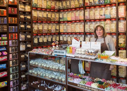 Interior with shop assistant and jars of traditional sweets, Olde Sweet Shop, Ipswich, Suffolk,