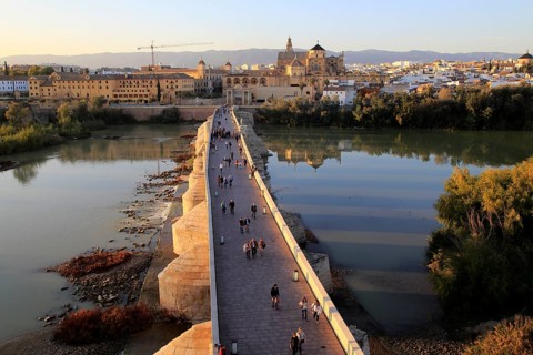 Roman bridge spanning river Rio Guadalquivir with Mezquita cathedral buildings, Cordoba, Spain,