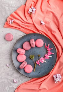 Purple and pink macaron or macaroon cakes with bleeding heart flowers and red textile on blue