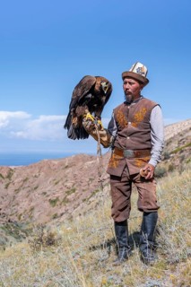 Traditional Kyrgyz eagle hunter with eagle in the mountains, near Kysyl-Suu, Kyrgyzstan, Asia