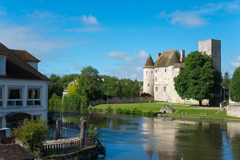 Historisches Schloss an einem Fluss mit üppiger grüner Landschaft und blauem Himmel, Château-Musée