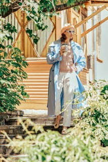 A fashionable woman walks down the steps of her wooden house in a quiet area of the city, holding a