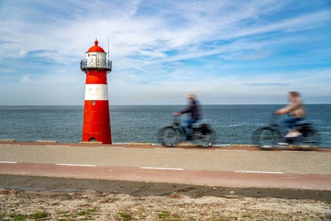 North Sea dyke near Westkapelle, Westkapelle Laag lighthouse, cyclists on the Zeeuwse Wind Route