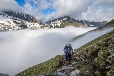 Mountaineers on a hiking trail, high fog in the valley, mountain peak above the clouds, summit