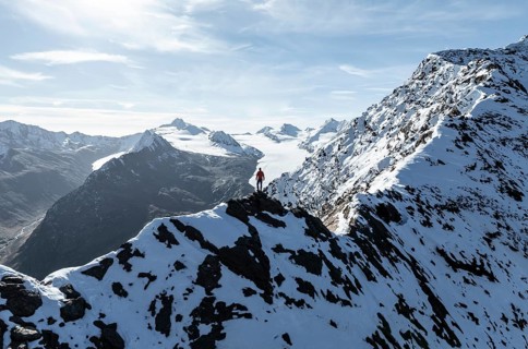 Mountaineer standing on the snow-covered Ramoljoch under a clear sky in the Alps, behind glacier