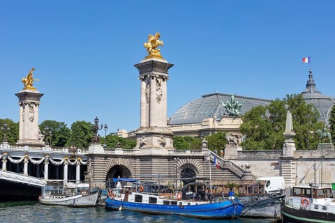 Boats on the river along the monumental bridge with golden sculptures, Paris