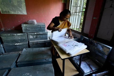 An official checks the documents submitted by people at an National Register of Citizens (NRC) Seva