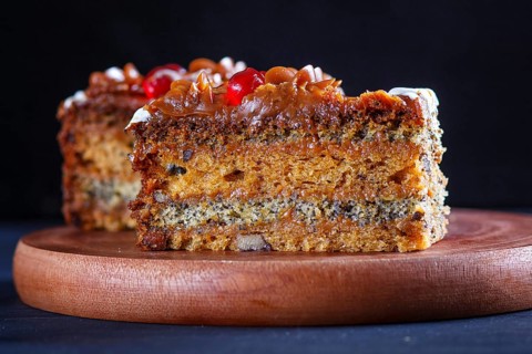 A piece of cake with caramel cream and poppy seeds on a wooden kitchen board. close up, selective