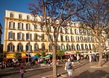 People sitting outside popular cafes on a sunny afternoon in Plaza de la Merced, Malaga, Spain,