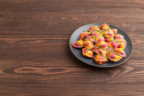 Rainbow colored dumplings with pepper, herbs, microgreen on brown wooden background. Side view,