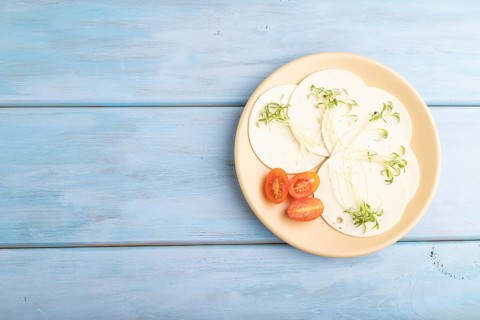 White cheese with tomatoes and cilantro microgreen on blue wooden background. top view, flat lay,