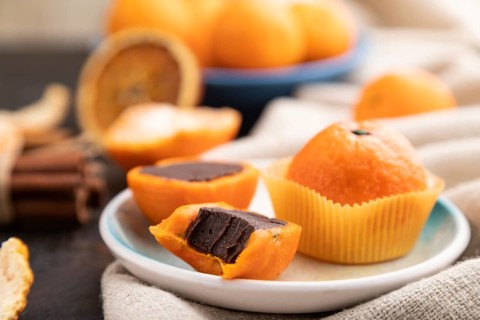 Truffle chocolate tangerine candies on a black concrete background and linen textile. Side view,