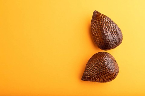 Salak or snake fruit on orange pastel background. Top view, flat lay, copy space. Tropical, healthy
