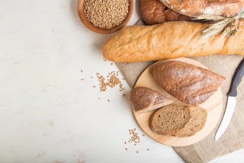 Sliced bread with different kinds of fresh baked bread on a white wooden background. top view, flat