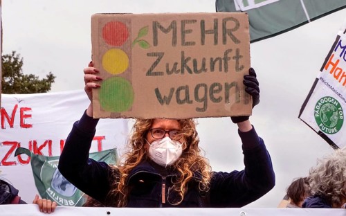 A demonstrator holds a sign with the Ampel logo and the words Mehr Zukunft wagen (Dare to have more