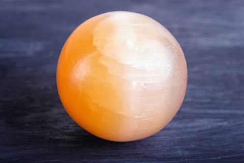Orange onyx sphere on a black background, close up