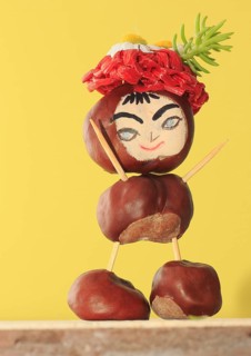 Funny chestnut figure with hat standing in front of a yellow wall, North Rhine-Westphalia, Germany,