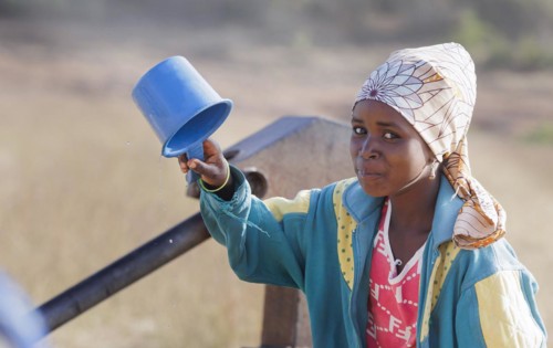 Young woman, girl drinking water from a plastic cup in Maraban Dare community in Plateau state,