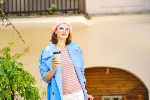 Beautiful brunette woman walks in the city with a cardboard glass of coffee in sunglasses