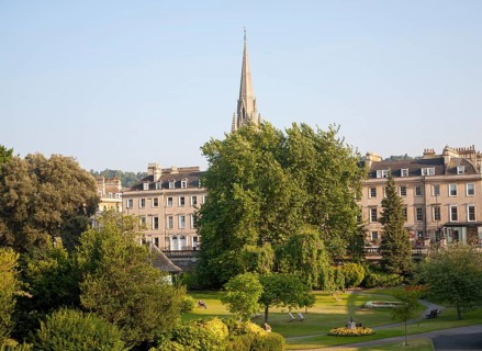 Parade Gardens public park in city centre of Bath, Somerset, England with church spire in