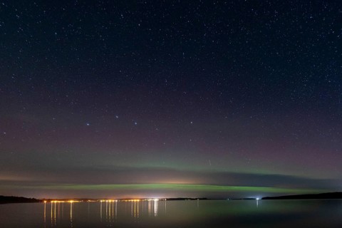 Northern lights (aurora borealis) shine on a starry night over Lake Plau, Ganzlin,