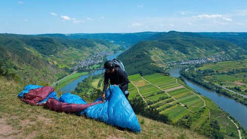 Paraglider prepares on the hill, with a wide view of the river and valleys, Paragliding, Bremm,