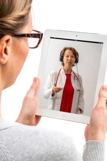 Symbolic image of telemedicine, patient speaking to a doctor in a video conference from home