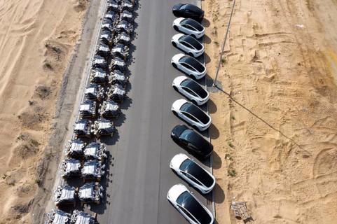Tesla Y models produced in the Tesla Giga Factory stand opposite vehicle components from the