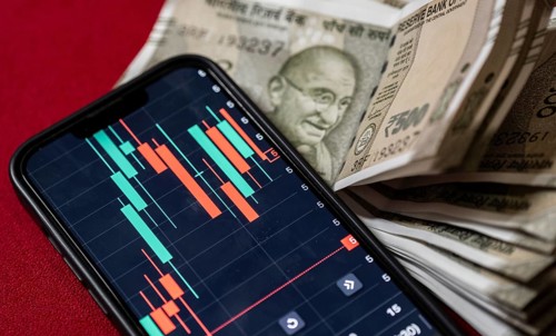 Stock market graph or chart display on a mobile phone against Indian 500 rupee paper currency note