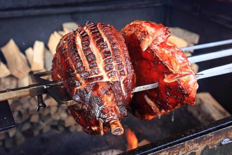 Pork knuckles are grilled on a spit over a wood fire
