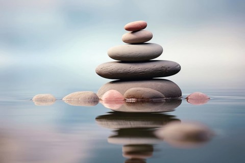 Stack of zen stones on water with a nature background. The image conveys a sense of balance,
