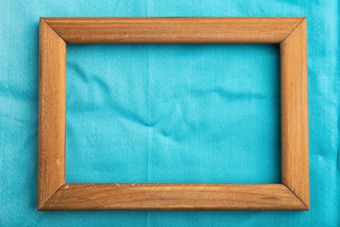 Wooden frame on smooth cotton blue tissue. Top view, flat lay, natural textile background and