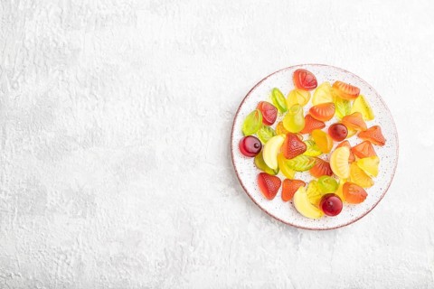 Various fruit jelly candies on plate on gray concrete background. top view, flat lay, copy space