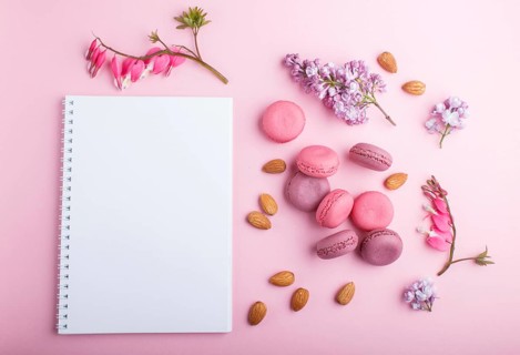 Purple and pink macaron or macaroon cakes with notebook and lilac and bleeding heart flowers on