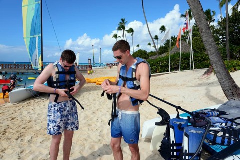 Two men prepare for sailing on sunny tropical beach, catamaran trip, Dominicus beach, Bayahibe,