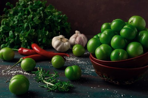 Tkemali, green cherry plum, with ingredients for sauce, cilantro, mint, hot pepper, garlic, on a
