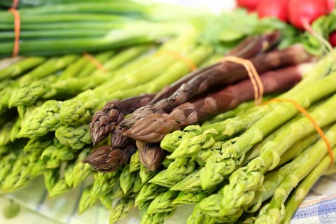 Green and purple asparagus, radishes in the background