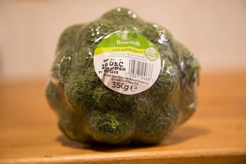 Broccoli head wrapped in plastic film with Tesco product label close up