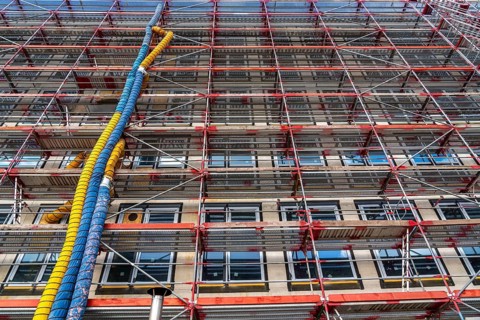 Large construction site, scaffolded shell of an office building complex, air hoses for building