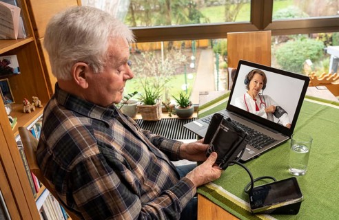 Symbolic image of telemedicine, elderly patient speaks to a doctor in a video conference from home,