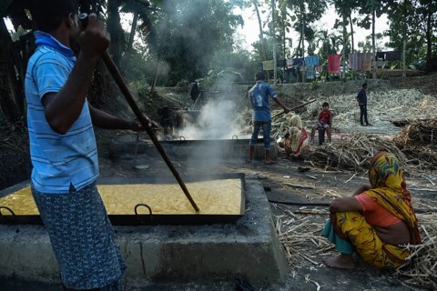 Workers boiling sugarcane juice as they are making Gur (jaggery) in a village on December 10, 2021