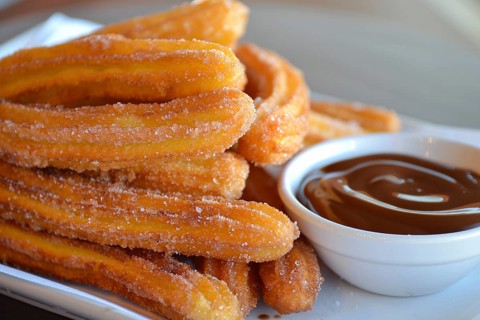 Close up of Churros with chocolate sauce on plate. A fried dough dessert from Spanish and