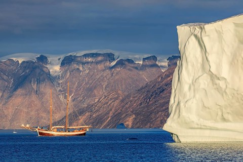 Sailing boat, ship in fjord in front of large icebergs and mountains, evening light, Scoresby