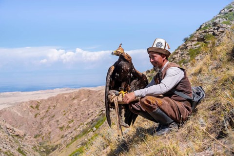 Traditional Kyrgyz eagle hunter with eagle in the mountains, near Kysyl-Suu, Kyrgyzstan, Asia