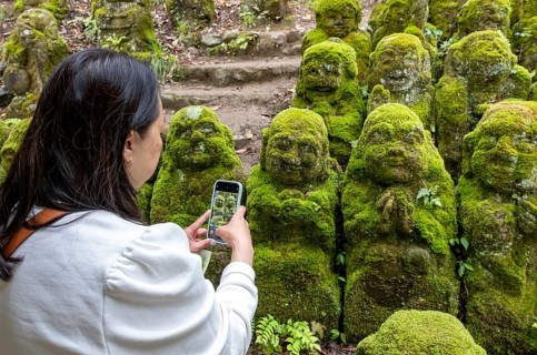 Visitor takes pictures of rakan statues at Otagi Nenbutsu-ji temple, Kyoto, Japan, Asia