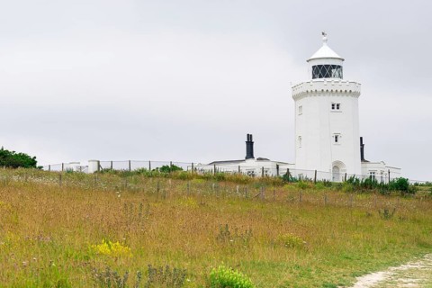A lighthouse overlooks a natural landscape under a cloudy sky, South Foreland Lighthouse, White