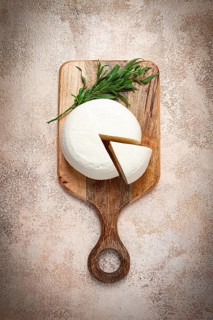 Head of Georgian cheese, Imereti variety, top view, on a cutting board
