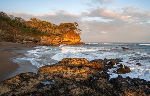 Sandy beach beach with rocks and sea at sunset, Playa Cocalito, coastal landscape, Pacific coast,
