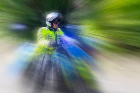 Policeman on a motorbike driving fast along the road, the speed is emphasised by the motion blur,