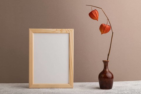 White wooden frame mockup with physalis in ceramic vase on beige paper background. Blank, vertical